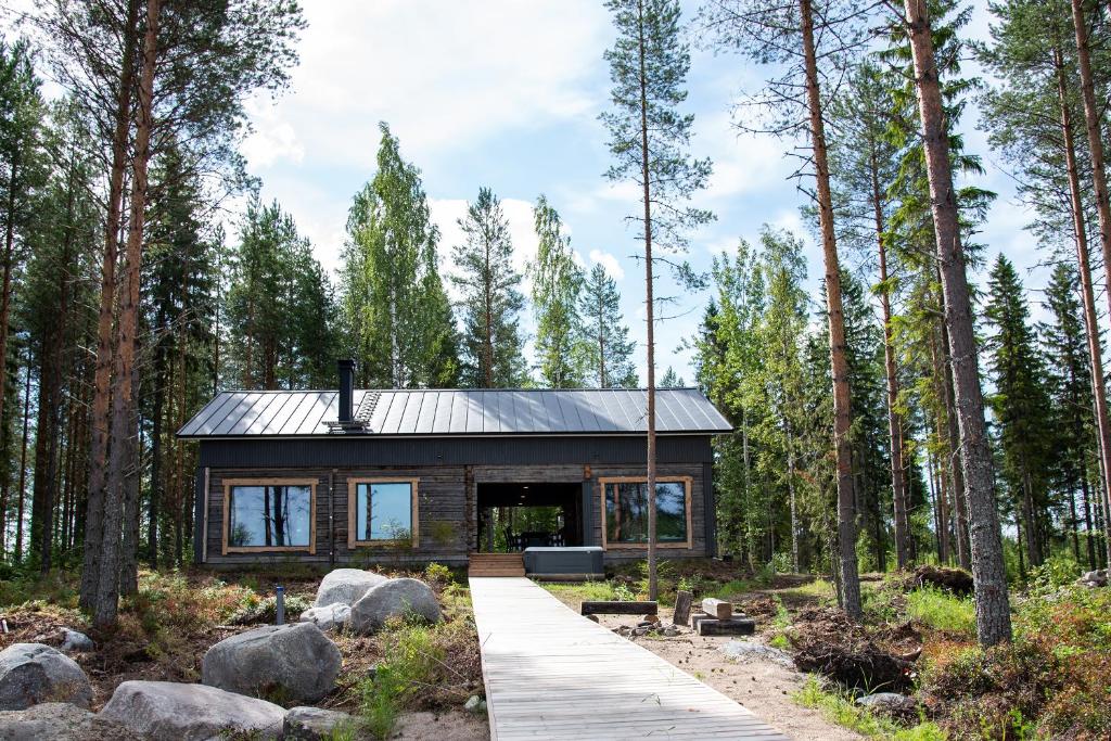 a house in the woods with a wooden walkway at Elon ranta in Alvajärvi