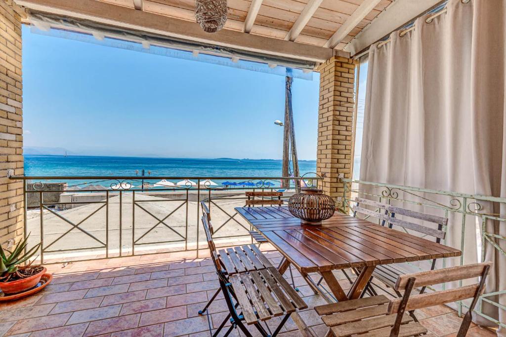 a table and chairs on a balcony with a view of the ocean at Seaview stone apartment in Ipsos Beach in Ipsos
