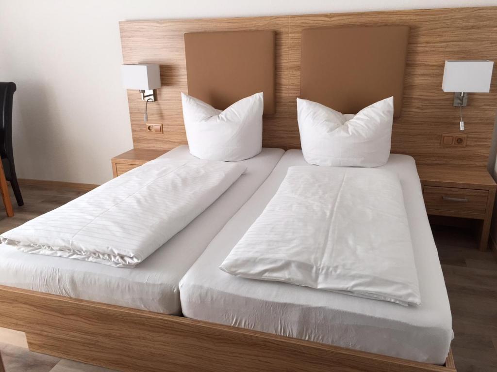 - un lit avec des draps et des oreillers blancs dans l'établissement Pension am Meer, à Norddeich