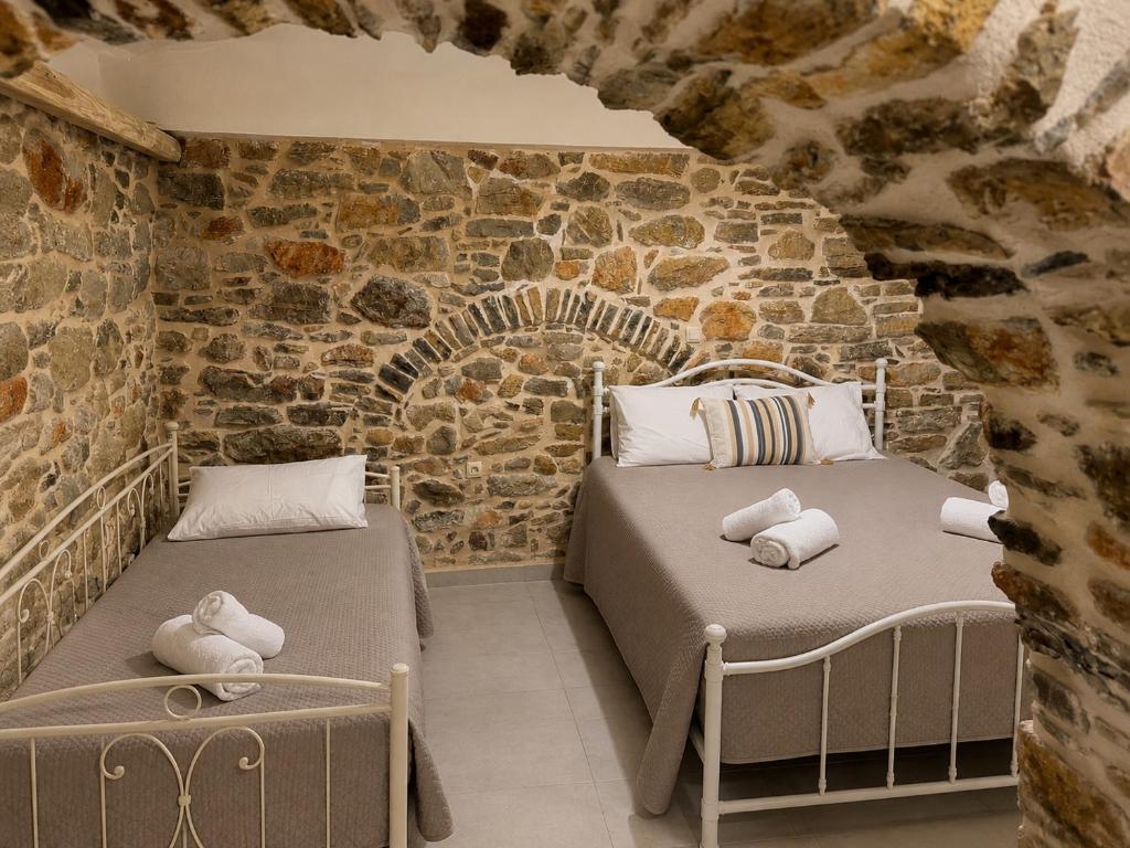 two beds in a room with a stone wall at Mastic Ev in Chios