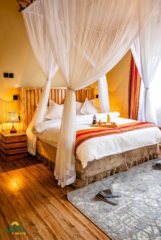 a bedroom with a large bed with curtains at Equator Lodge & Campsite in Kikorongo