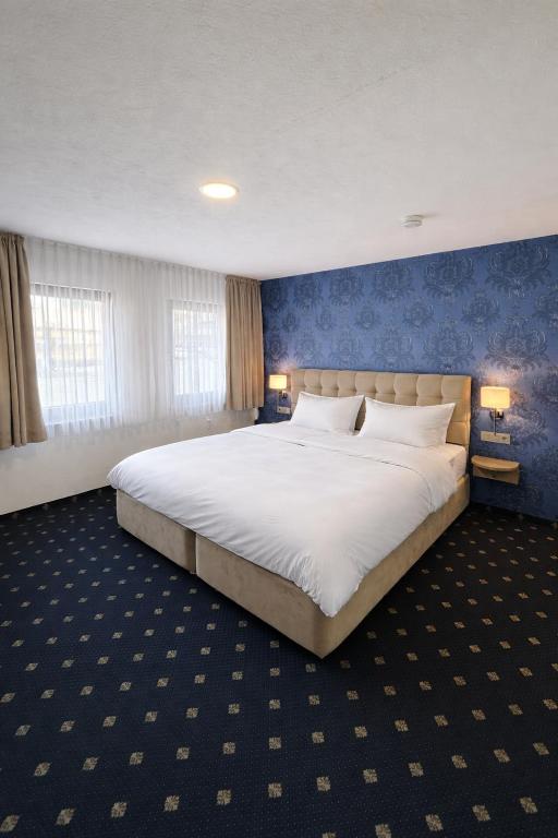 a bedroom with a large white bed with blue walls at WaldGold Aparthotel in Nagold