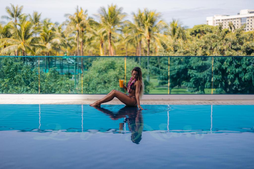 a woman sitting on the edge of a pool with a drink at Hotel La Croix in Honolulu