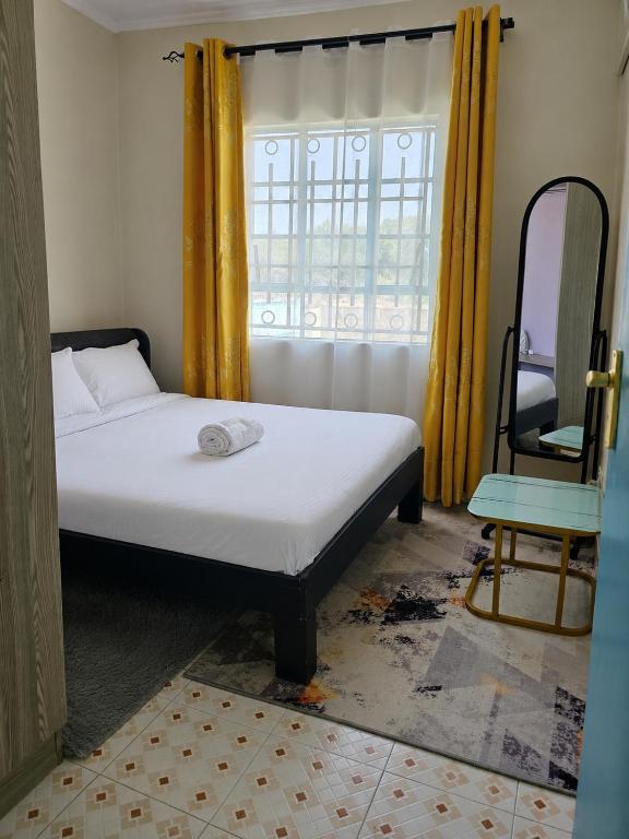 a bedroom with a bed and a chair and a window at LaDee Homes Cozy 1 bedroom in Kakamega - Old National Housing Estate in Kakamega