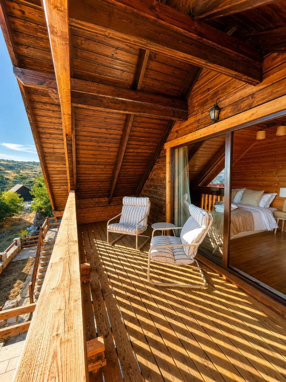 a room with a bed and two chairs on a deck at Chalet O Refúgio 2 in Penhas da Saúde