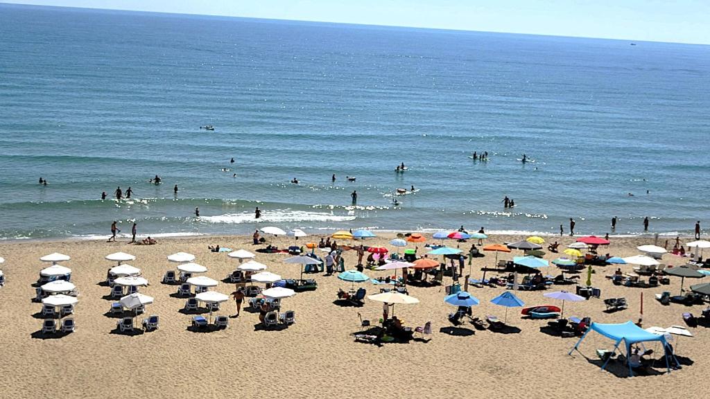a beach with many umbrellas and people in the water at Seafront Apartment im Obzor Beach Resort in Obzor
