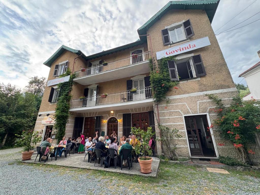 a group of people sitting at tables outside of a building at Govinda in Pontinvrea