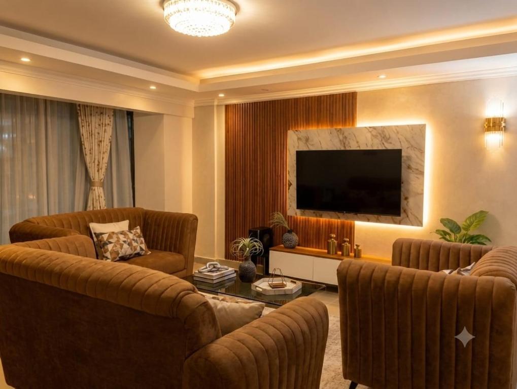 a living room with two couches and a flat screen tv at Lakeview 3BR Apartment Nakuru CBD in Nakuru