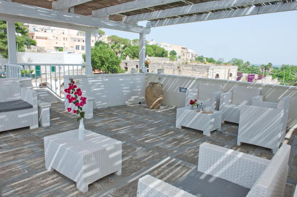 a white patio with white chairs and tables and flowers at Corte della Luce in Ugento