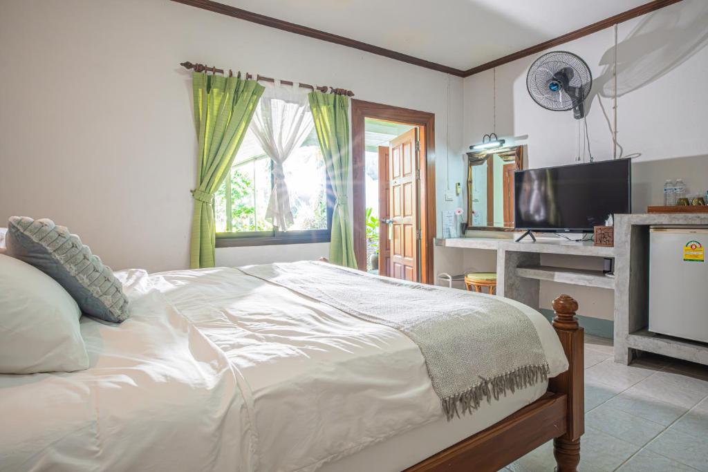 a bedroom with a white bed and a television at The Houme - Fisherman Village in Bophut