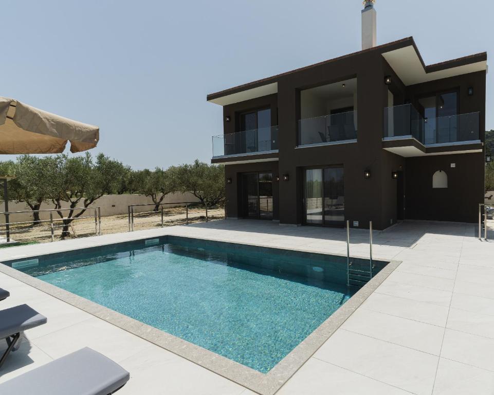 a villa with a swimming pool in front of a house at Athena Villas in Vasilikos