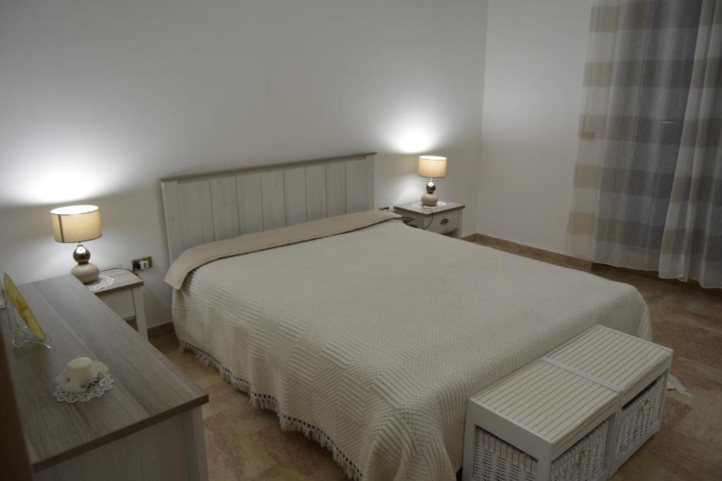ポリニャーノ・ア・マーレにあるCasa Angyのベッドルーム1室(ベッド1台、テーブル2台、ランプ2つ付)