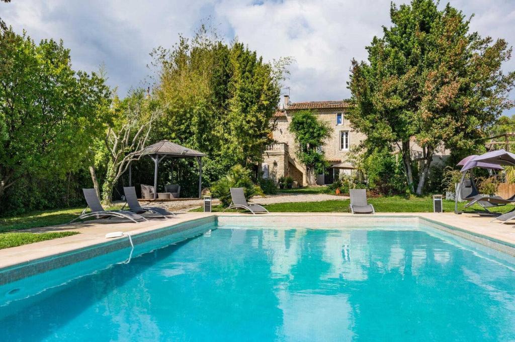 a swimming pool with chairs and a house at Clos de la Colombe in Pouzols
