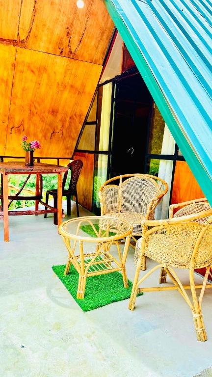 a patio with wicker chairs and a table in a tent at Ella Jungle Rock in Ella