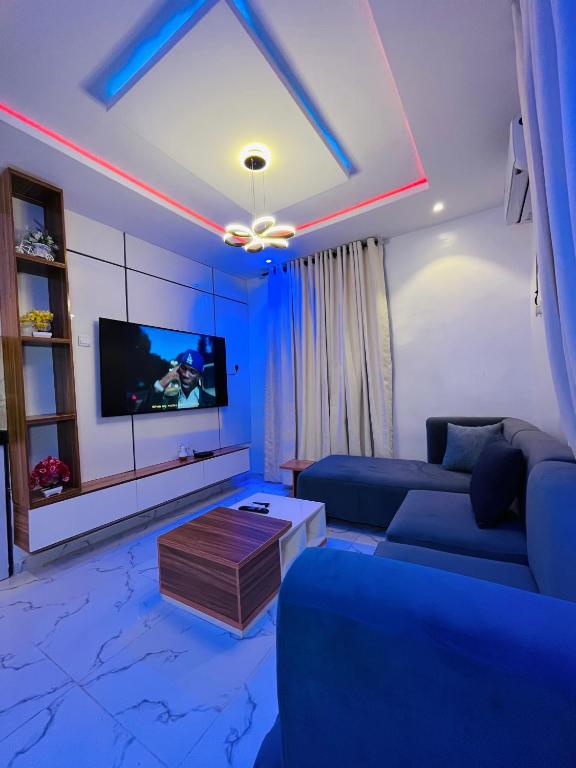a blue living room with a couch and a tv at Flexxy Apartment Hotel in Oshogbo