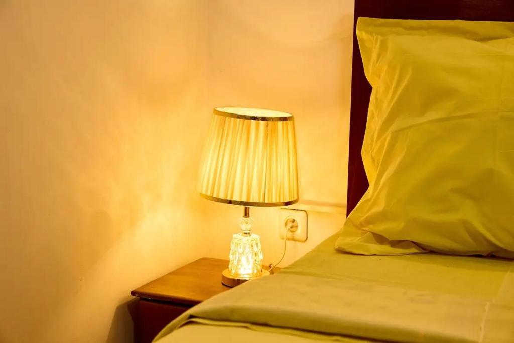 a lamp on a night stand next to a bed at Bj House in Douala
