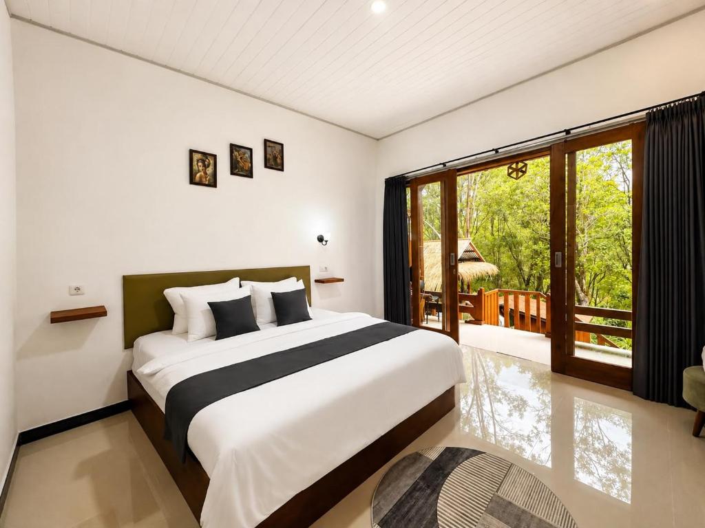 a bedroom with a large bed and a balcony at Tegal Luwih Cabin in Munduk