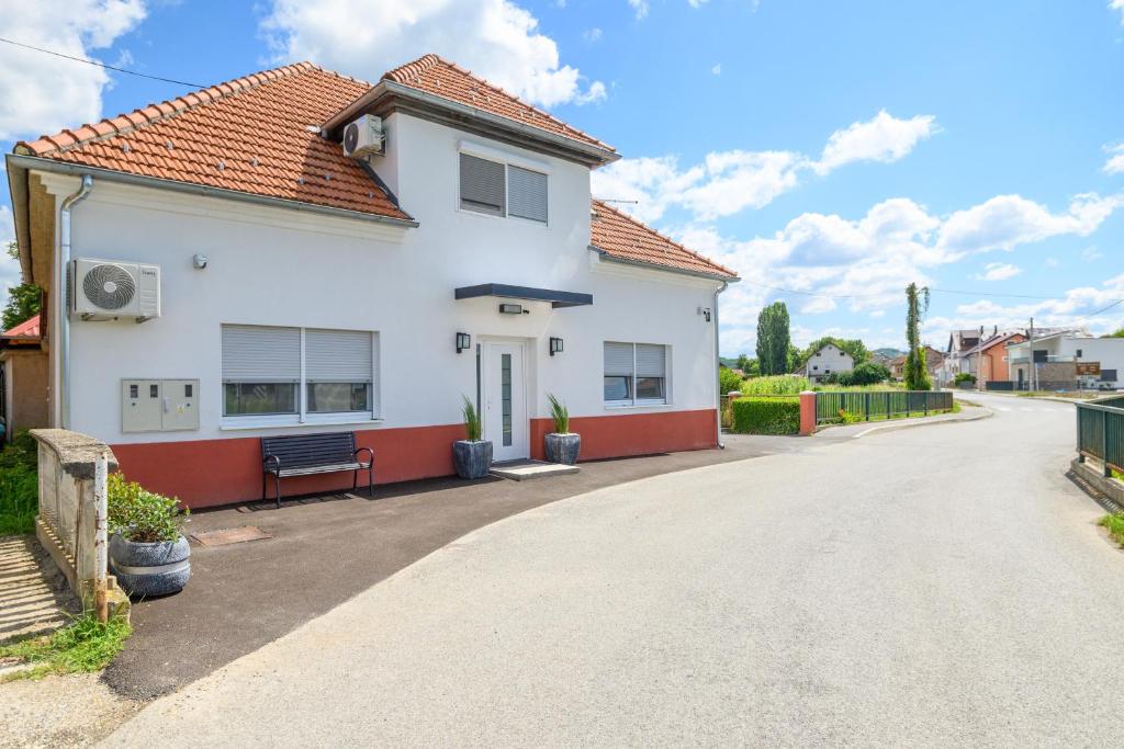 a white house with a bench in the driveway at Apartment Mamma in Začretje