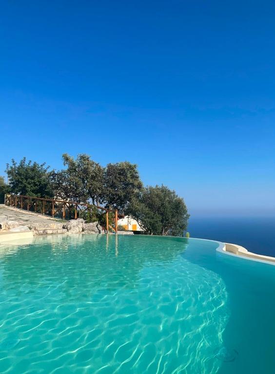 a pool of blue water with trees in the background at Tenuta La Picola in Furore