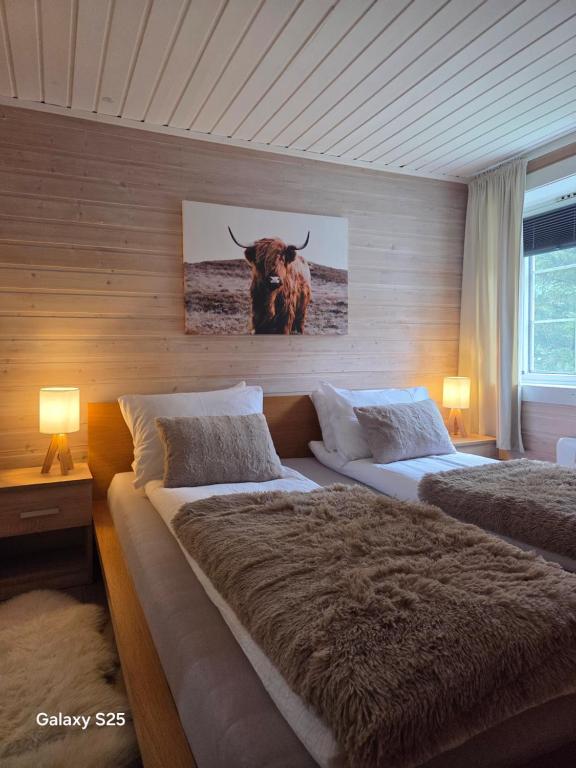 a bedroom with two beds and a bull on the wall at En liten hytte i Gryllefjord in Gryllefjord