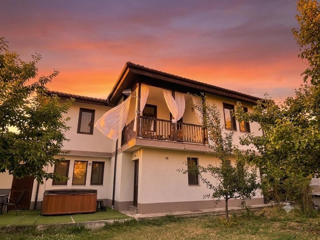 a house with a balcony at sunset at Kassandrova Guest House & Spa in Bratsigovo