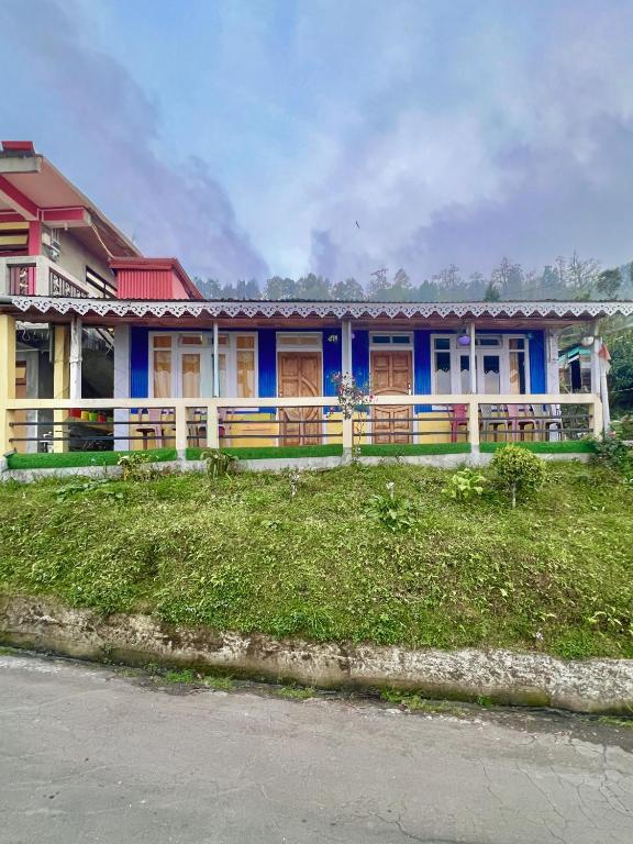 a blue and white house with a green yard at Dawaipani Sona Homestay in Jālāpahār