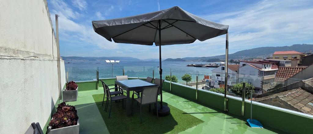 a table and chairs on a balcony with an umbrella at Casa da Banda in Bueu