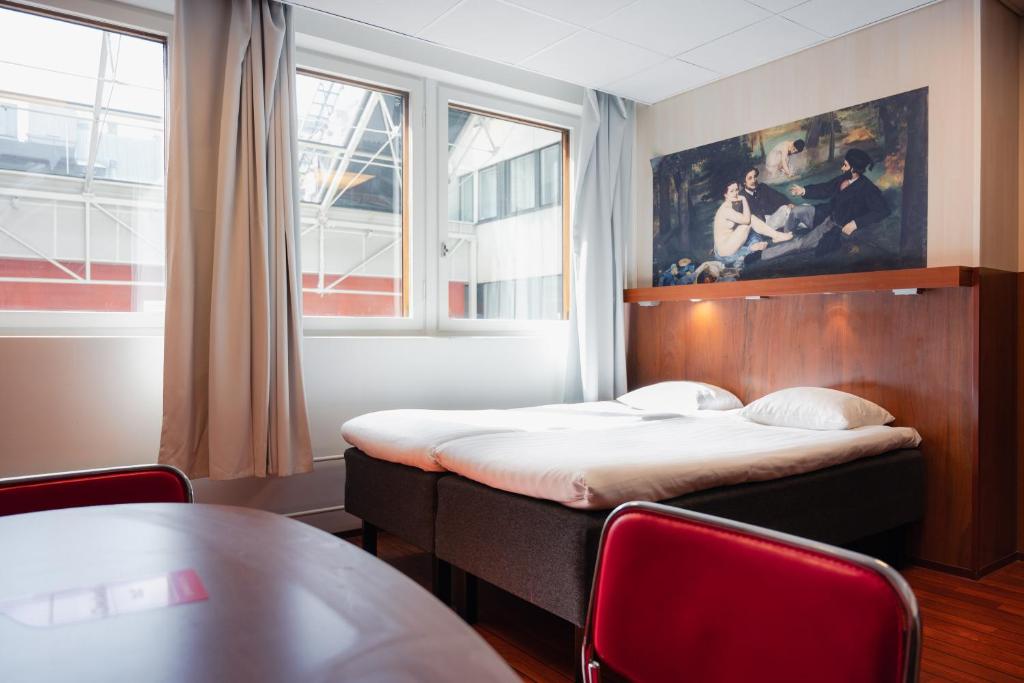 a bedroom with a bed and a table and a window at Omena Hotel Helsinki City Centre in Helsinki