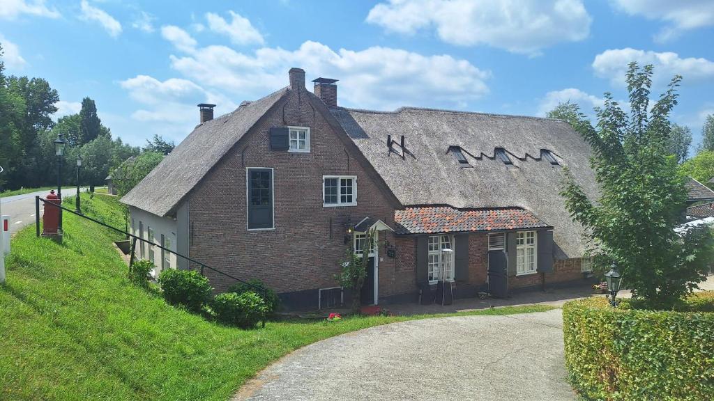 an old brick house with a thatched roof at Herberg de Lingehoeve in Oosterwijk