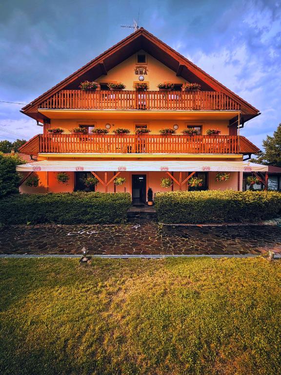 a large house with a large balcony on top of it at Penzion UNA in Liptovský Ján