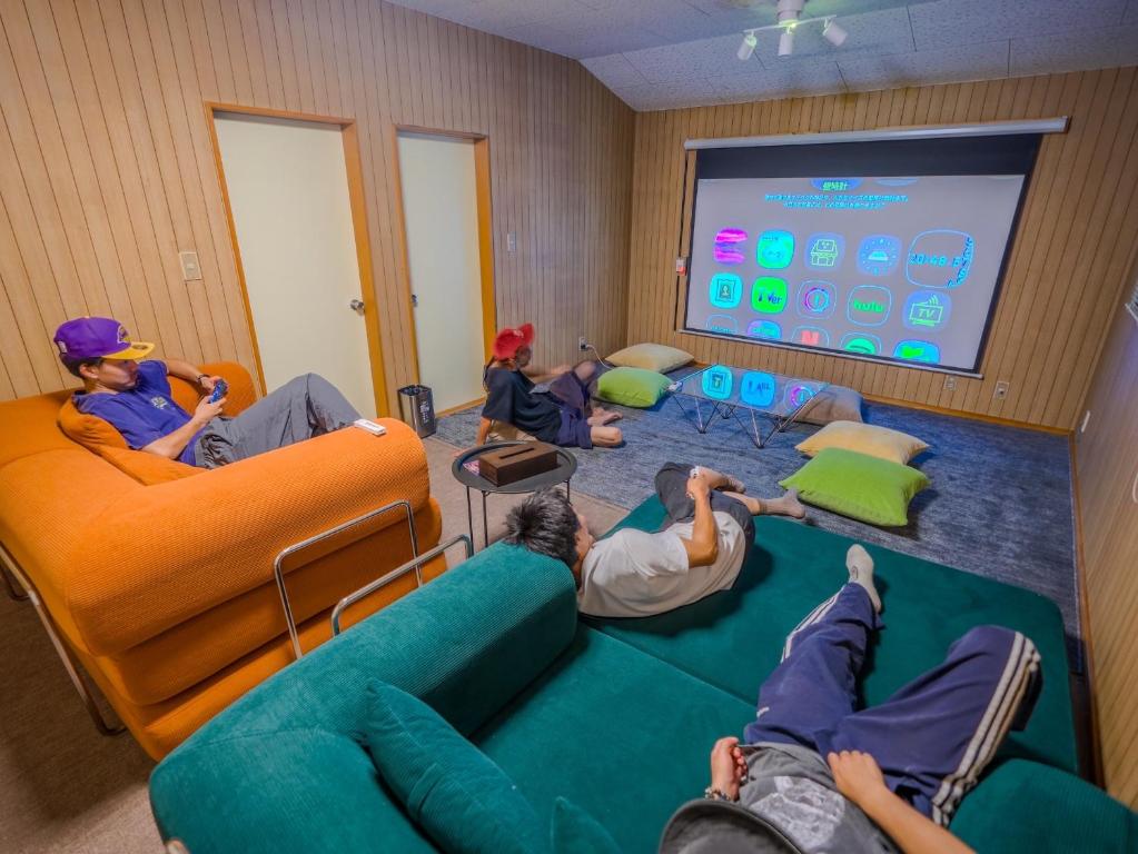 a group of people sitting in a room watching a screen at 天然温泉付 一棟貸し最大12名 近隣施設事前予約で バーベキュー 花火 和羽灯屋 ナウヒヤ in Fuefuki