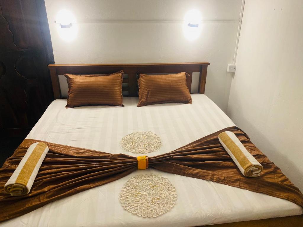 a bed with a brown and white comforter and pillows at JA Villa in Pottuvil