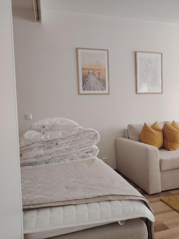 a white bedroom with a bed and a couch at Rauhallinen majoitus parvekkeella in Joensuu