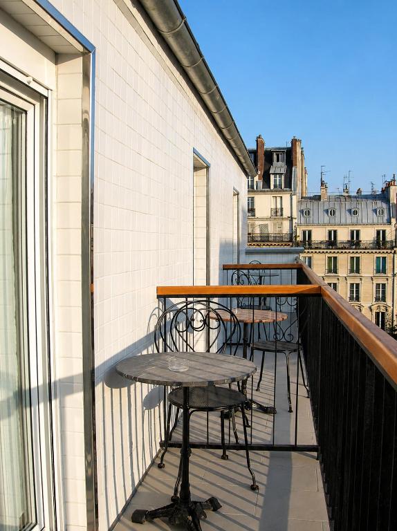 a balcony with tables and chairs on a building at Hotel Darcet in Paris