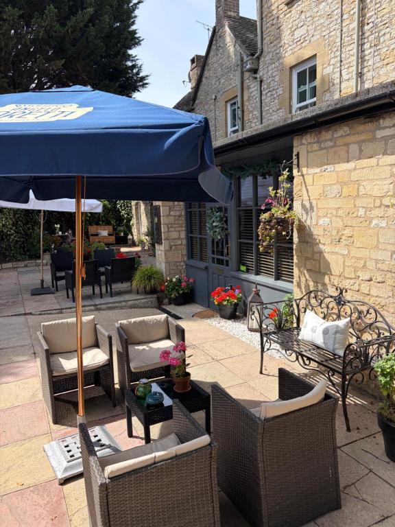 a patio with chairs and a blue umbrella at Burford Lodge - Adults only in Burford