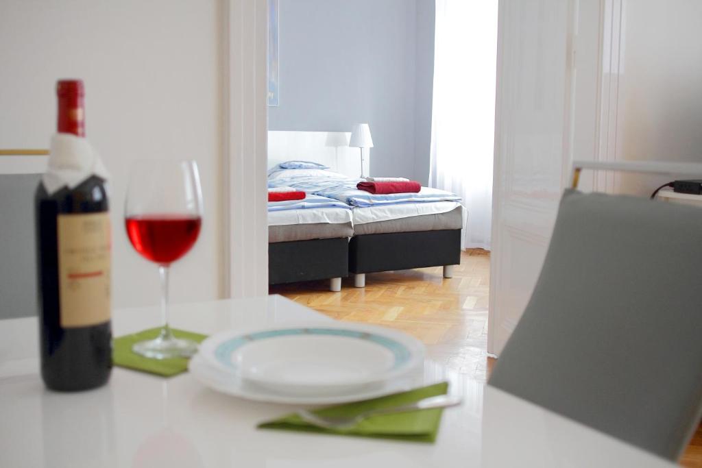 una mesa con una copa de vino y una botella de vino en City Centre Cosy Apartments, en Budapest