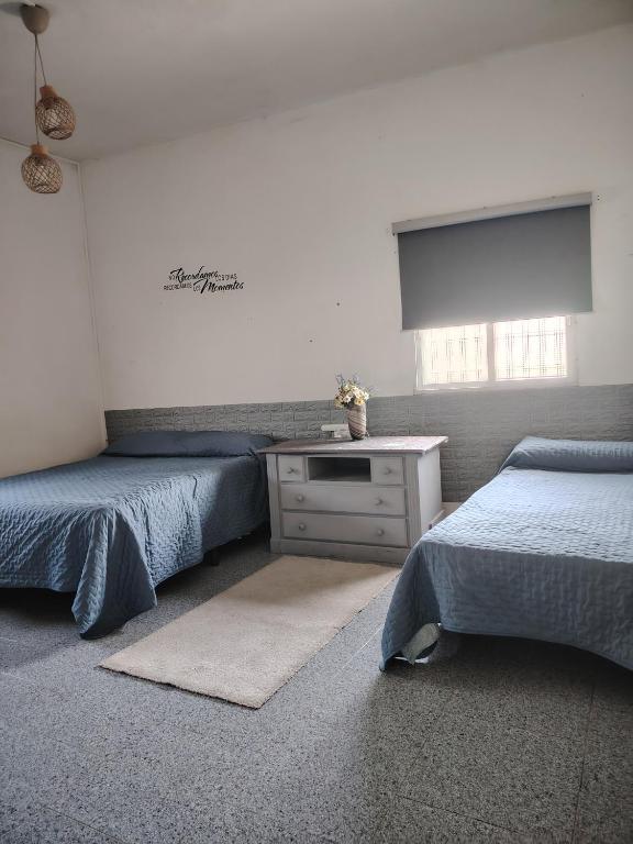 a bedroom with two beds and a table and a window at Casa adosada con patio in Jerez