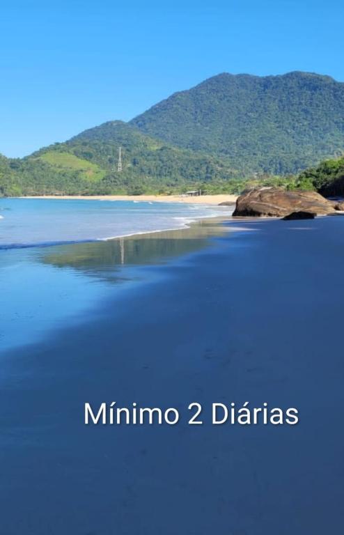 a body of water with a mountain in the background at Manacá Suítes Prumirim in Ubatuba