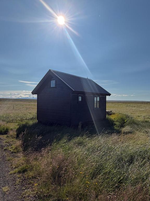a black shack in a field with the sun shining at Egilsstaðir 1, Sjónarhóll, Urridafossvegur, Selfoss in Selfoss