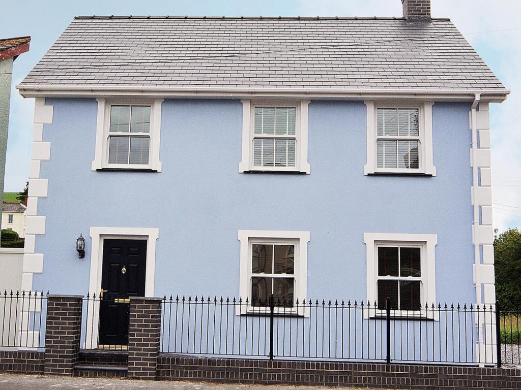 a blue house with a white fence at Ty Ffynnon - Hw7601 in Llansantffraid
