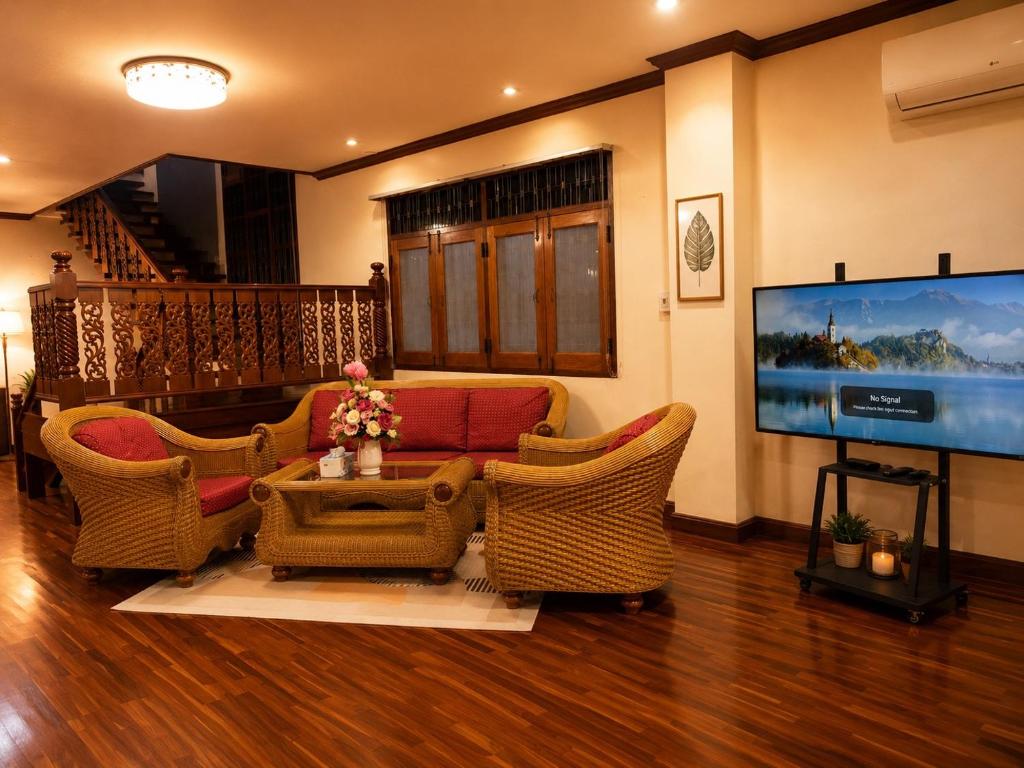 a living room with wicker furniture and a flat screen tv at Kat's GuestHouse in Hua Hin