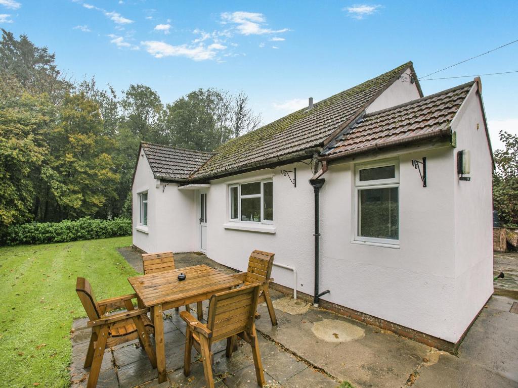 a white cottage with a wooden table and chairs at Spruce Cottage - Uk46875 in Hartland
