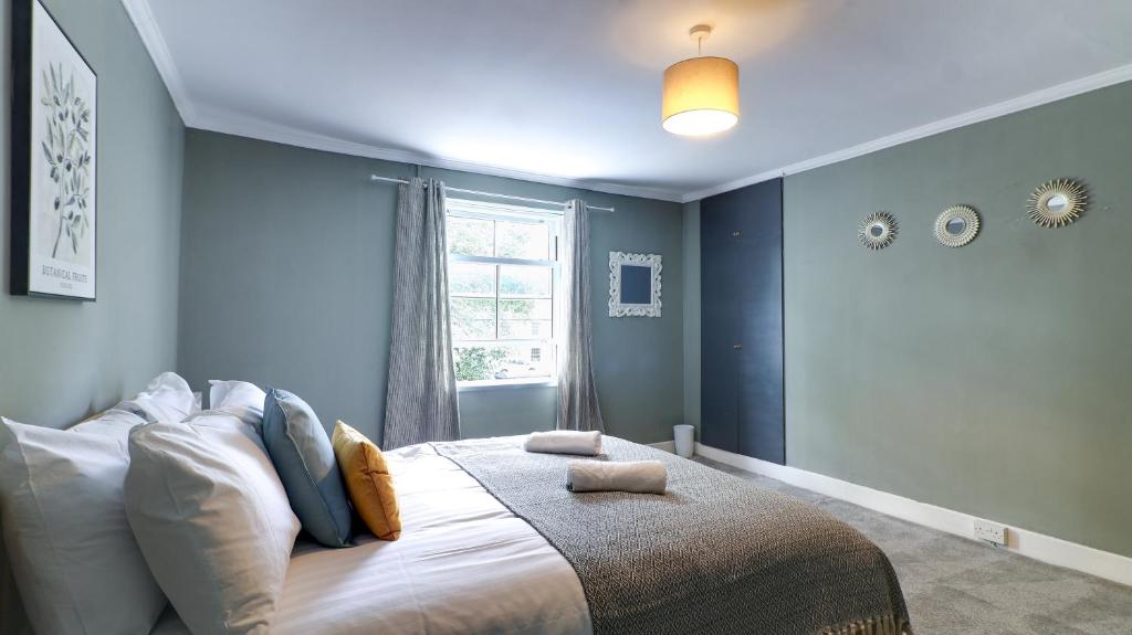 a bedroom with a bed with blue walls and a window at Delightful Durham Home in Gilesgate