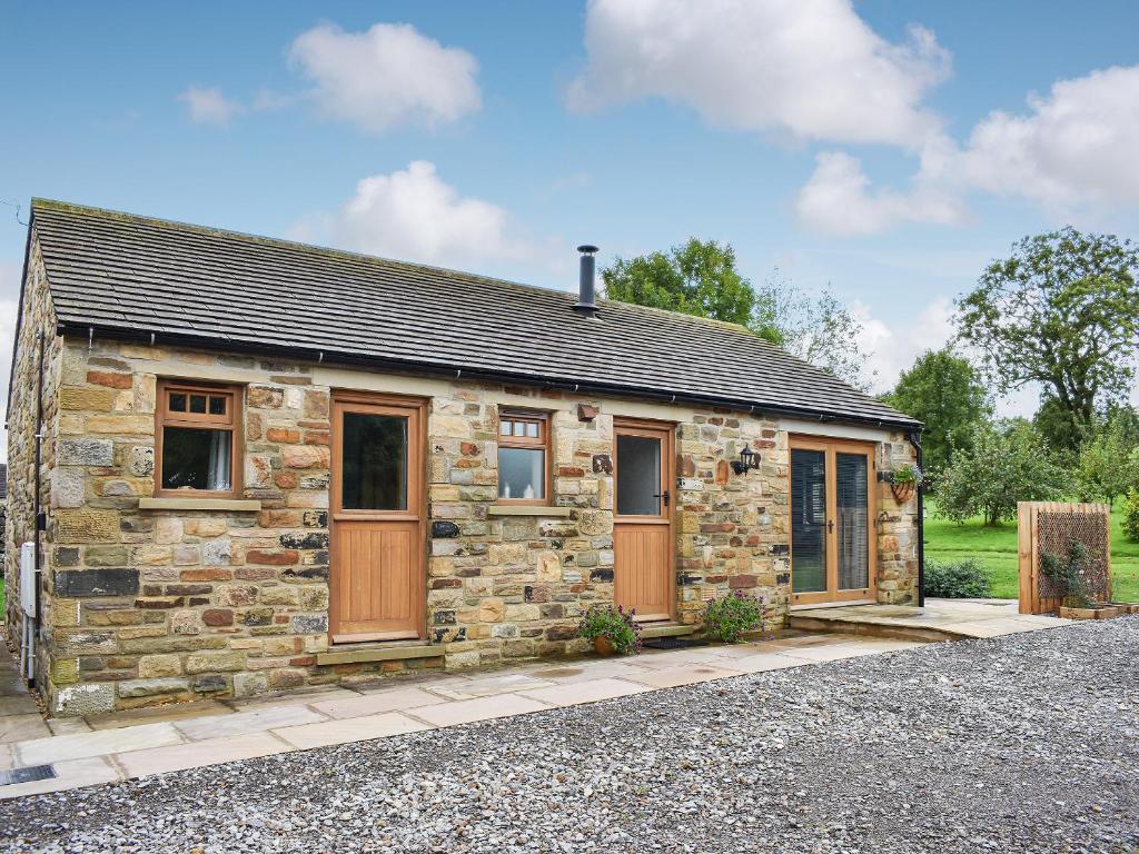 a stone house with wooden doors on a driveway at Brooklands Cottage in Bellerby