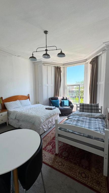 a living room with two beds and a table at Spacious Triple Studio Room, Private En-Suite & Kitchenette R6 in Sketty