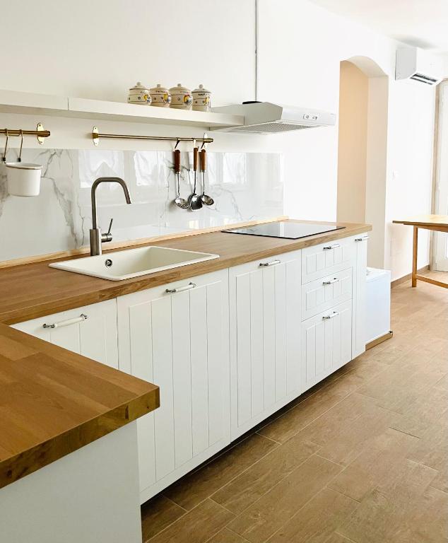 a kitchen with white cabinets and a sink at Apuliantales Cottage Bari in Carbonara di Bari