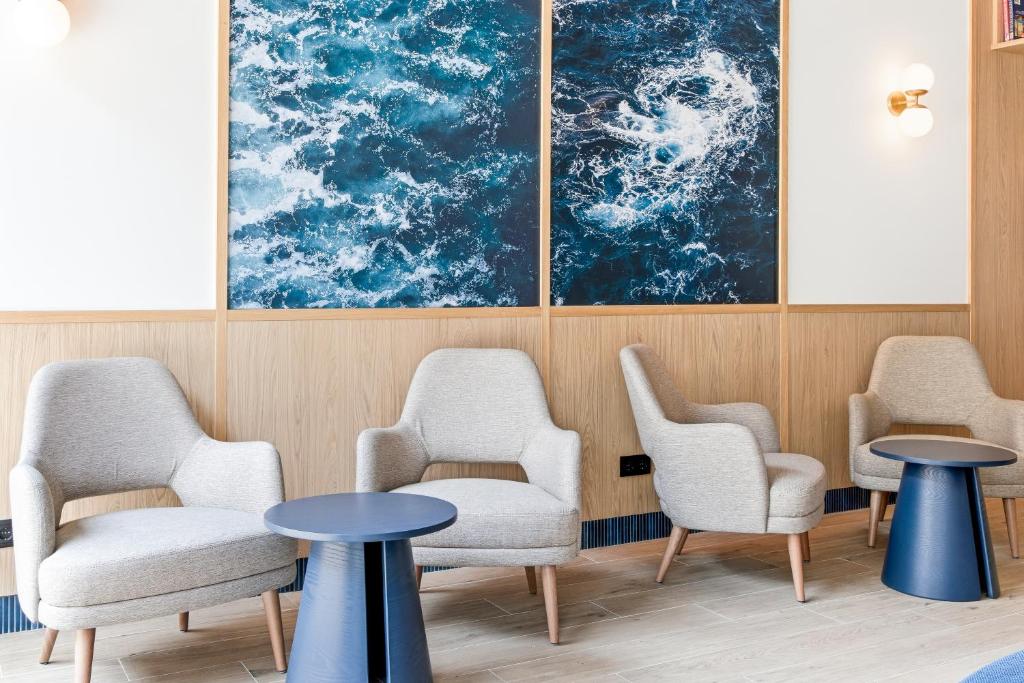 a waiting room with chairs and tables and a painting at B&B HOTEL A Coruña Aeropuerto in Culleredo