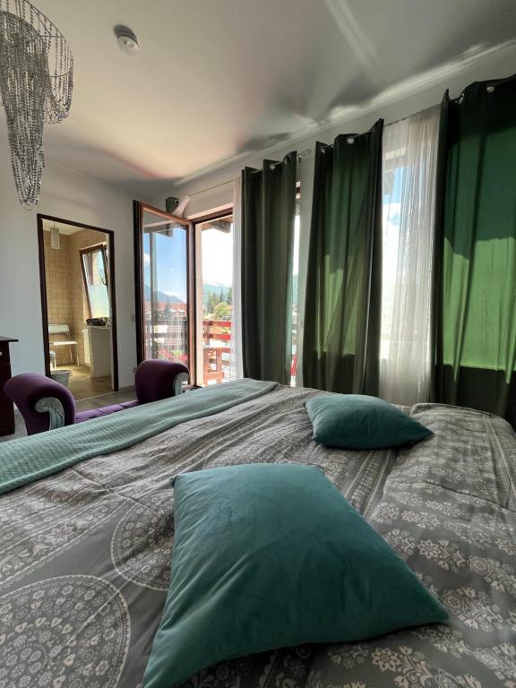 a bedroom with a large bed with green pillows at Vila Mama Jana in Buşteni