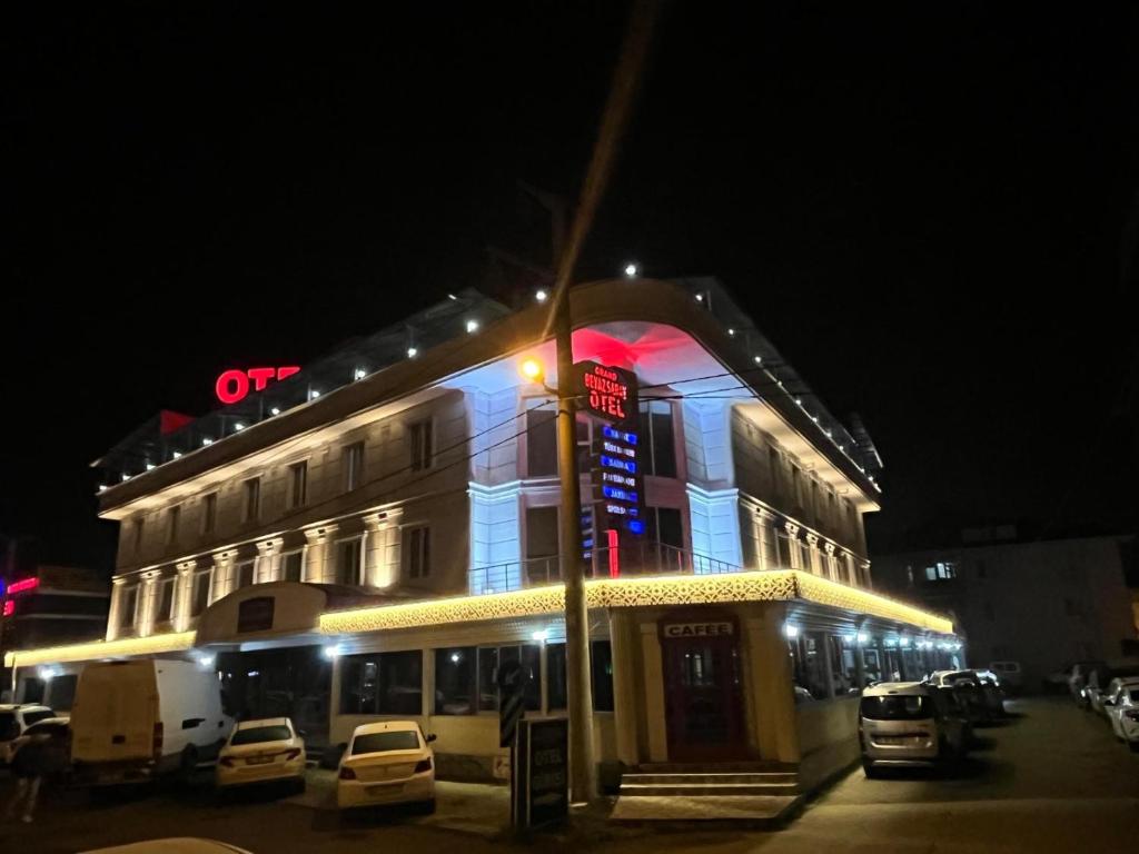 a lit up building with cars parked outside at night at Grand Beyaz Saray Otel in Duzce