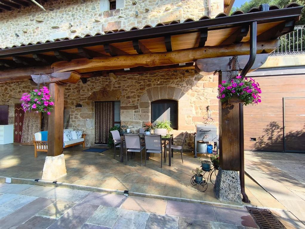 a patio with a table and chairs under a wooden pergola at Casa Mi Capricho in Concejero
